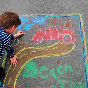 Student drawing with chalk on sidewalk